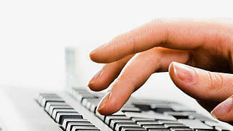 Das Bild zeigt eine Hand, die auf einer Tastatur etwas tippt. 